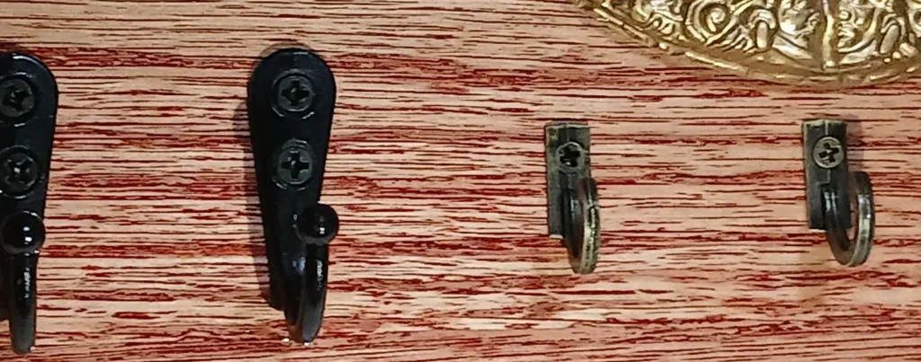 Detalle de ganchos metálicos en porta llaves de madera.